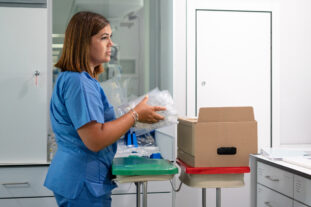 Lab relocation specialist carefully packing sample vials into a specimen transport box.