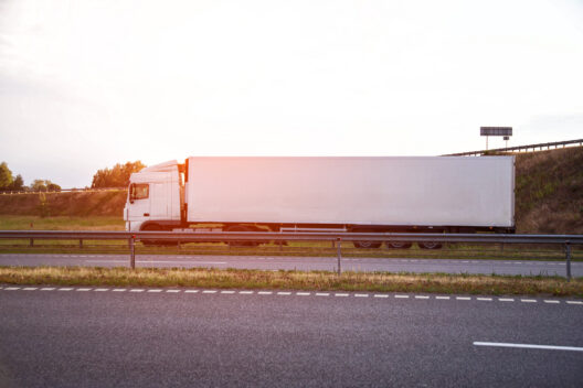 White refrigerated trailer on a highway, representing how pharma cargo is handled through cold chain material relocation.