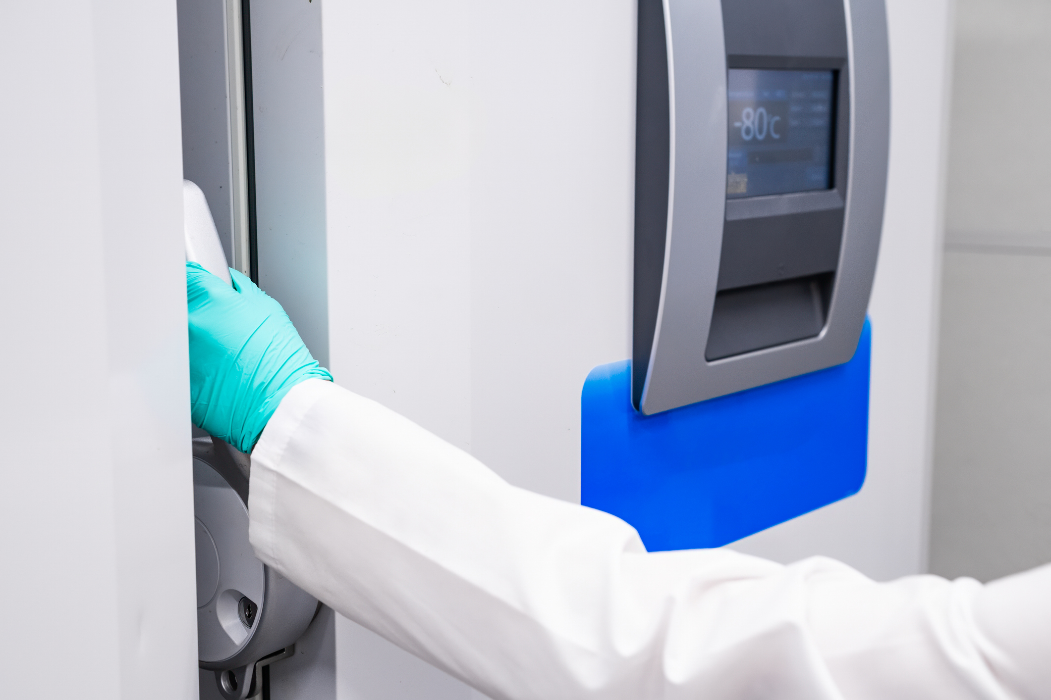Lab technician closing a −80°C ULT freezer during the laboratory relocation process.